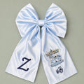 Oversized ice blue silk announcement bow with a navy embroidered initial on one tail and a carousel with It's a Boy lettering on the other