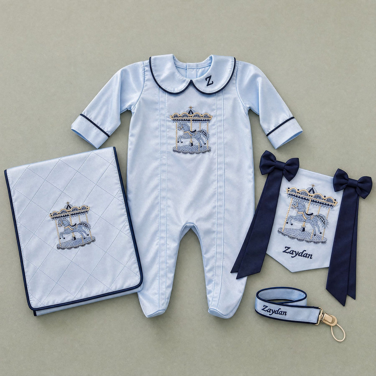 Welcome to the World ice blue gift bundle laid out flat — personalised ice blue silk romper, wrapping sheet, name flag and pacifier holder