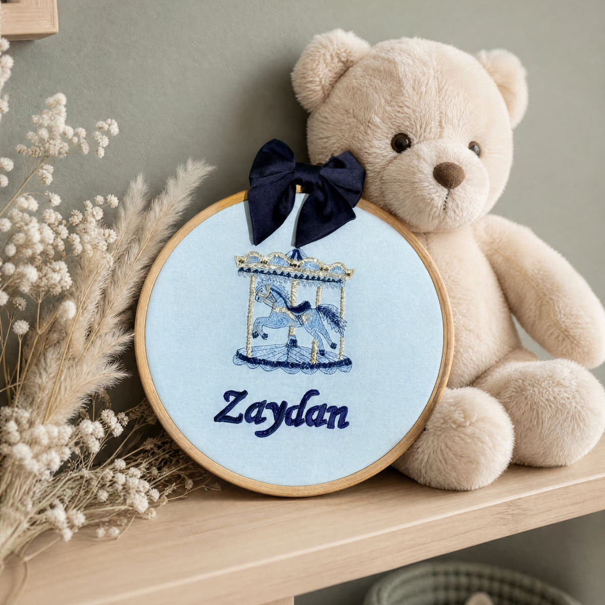 Ice blue silk name frame in a wooden hoop, styled in a nursery setting