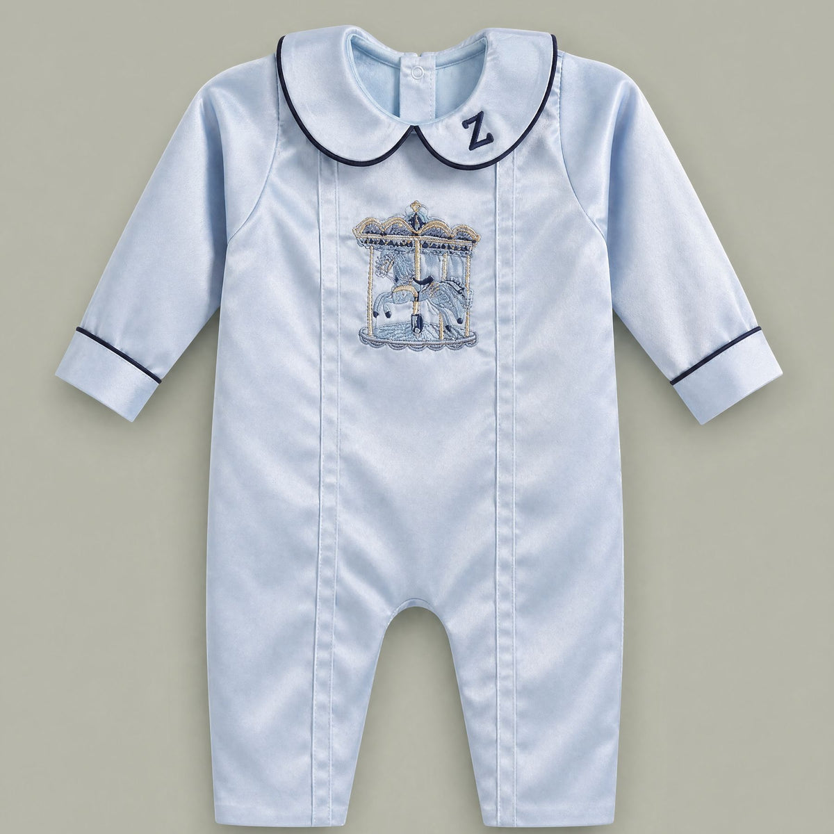 Ice blue silk baby romper with navy piping, an embroidered initial on the Peter Pan collar and a carousel motif with gold canopy at the chest