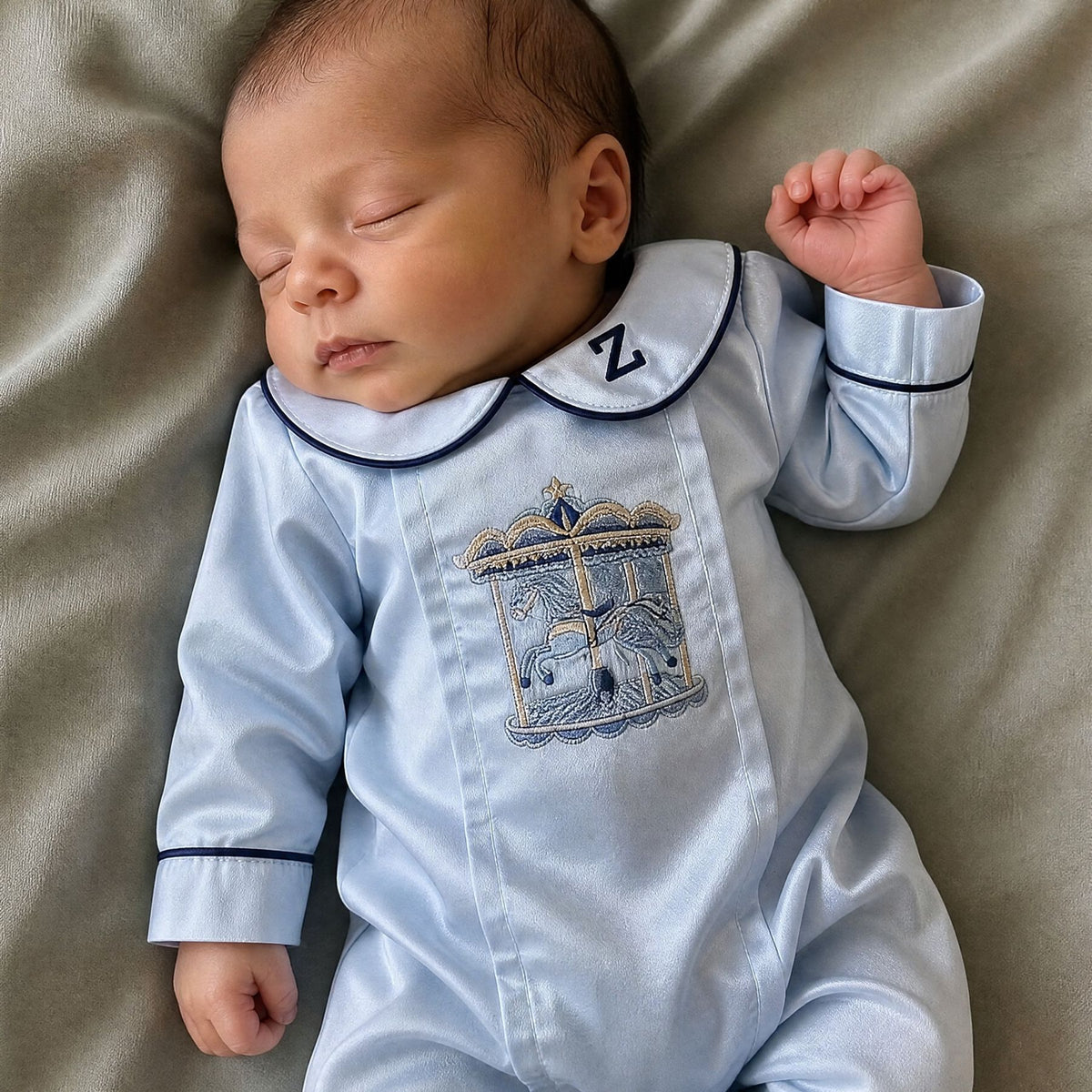 Ice blue silk Zyra Baby romper with navy detailing, styled in a nursery setting