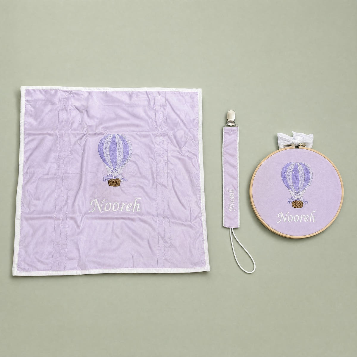 Just the Essentials lilac gift bundle laid out flat — personalised lilac silk wrapping sheet, name frame and pacifier holder