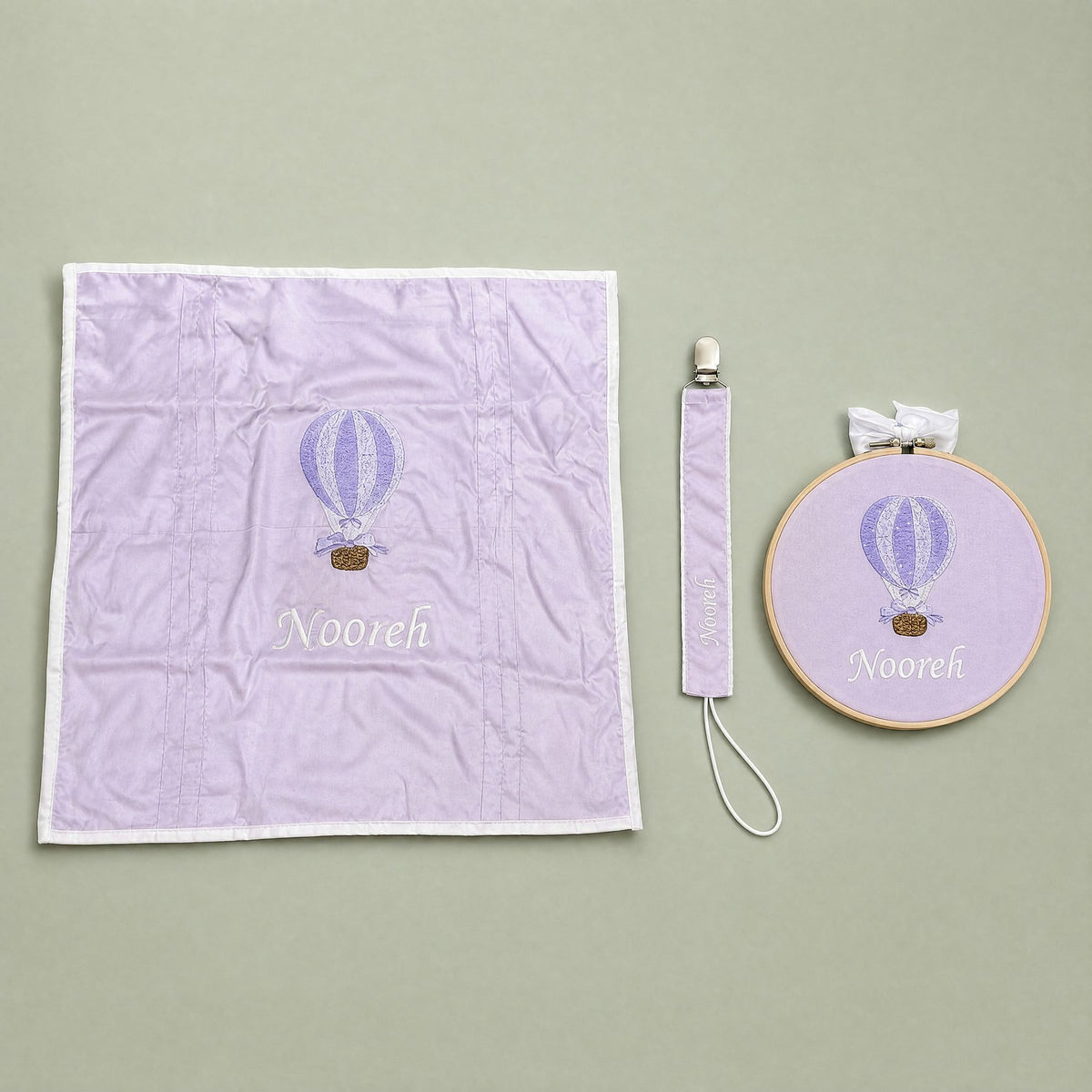 Just the Essentials lilac gift bundle laid out flat — personalised lilac silk wrapping sheet, name frame and pacifier holder
