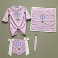 Welcome to the World lilac gift bundle laid out flat — personalised lilac silk romper, wrapping sheet, name flag and pacifier holder