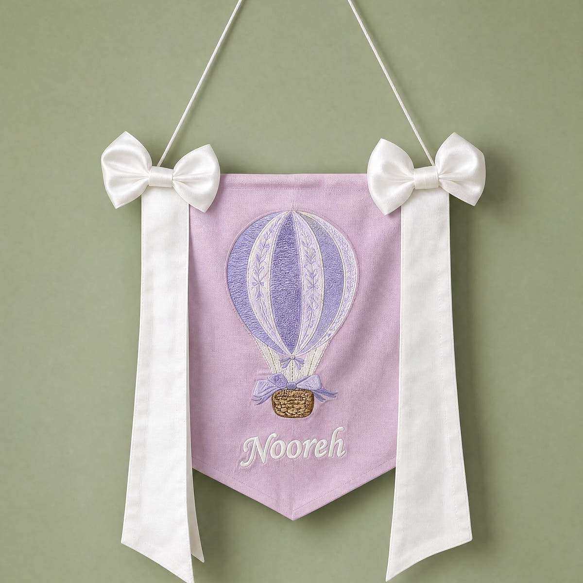 Lilac silk name flag with an embroidered hot air balloon, ivory silk bows and a baby's name in ivory script