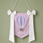 Lilac silk name flag with an embroidered hot air balloon, ivory silk bows and a baby's name in ivory script