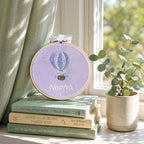 Lilac silk name frame in a wooden hoop, styled in a nursery setting