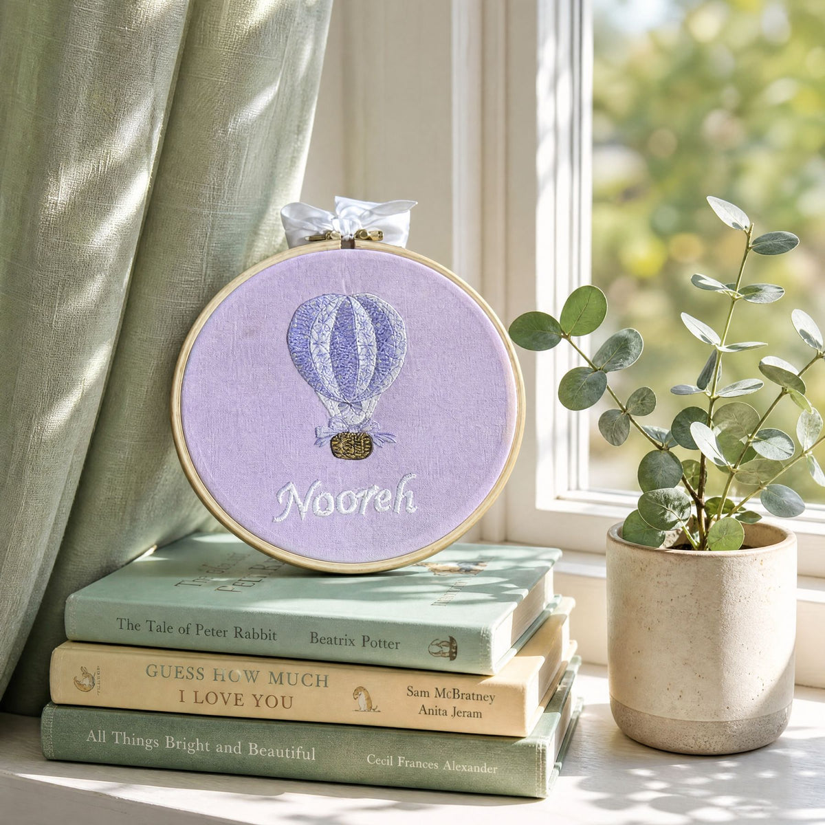 Lilac silk name frame in a wooden hoop, styled in a nursery setting