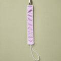Lilac silk pacifier holder with ivory detailing and a baby's name embroidered in ivory script