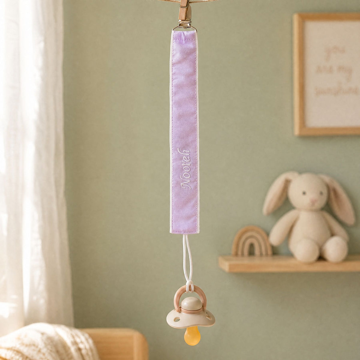 Lilac silk pacifier holder styled in a nursery setting