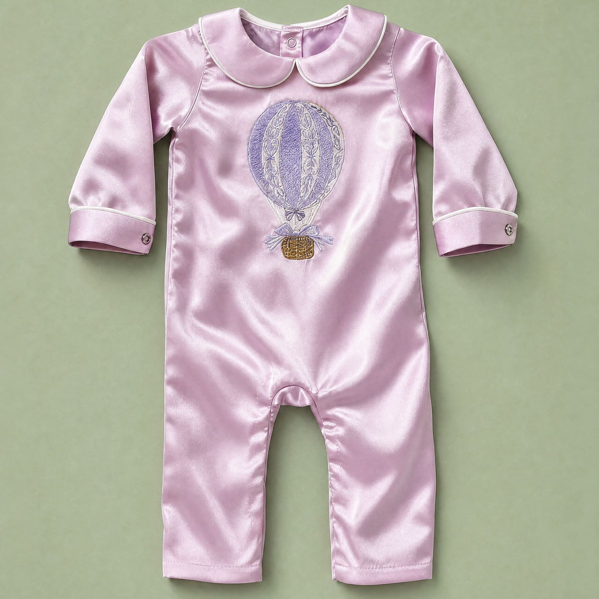 Lilac silk baby romper with ivory piping, a Peter Pan collar and an embroidered hot air balloon with a gold basket at the chest