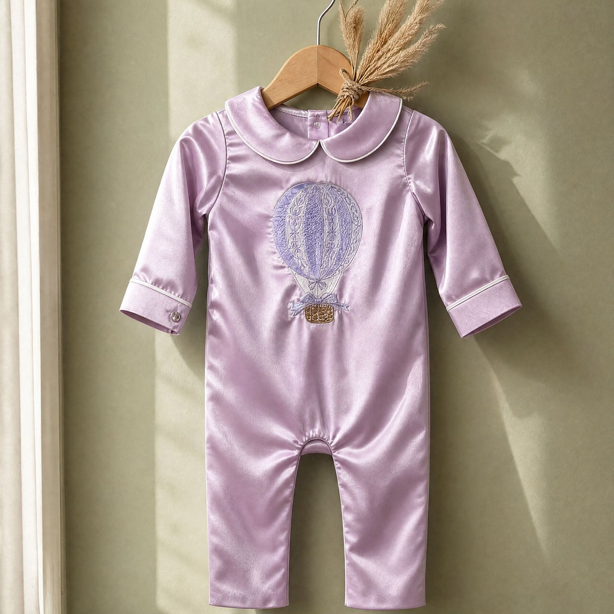 Lilac silk Zyra Baby romper with ivory detailing, styled in a nursery setting