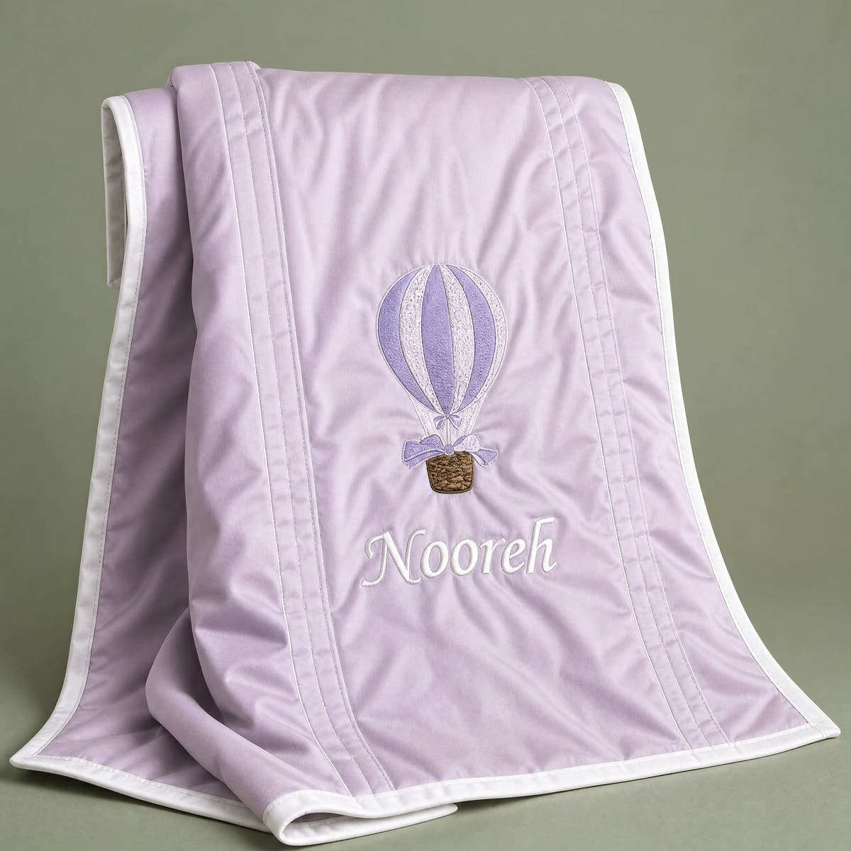 Lilac silk baby wrapping sheet with ivory trim, an embroidered hot air balloon and a name in ivory script