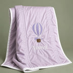 Lilac silk baby wrapping sheet with ivory trim, an embroidered hot air balloon and a name in ivory script
