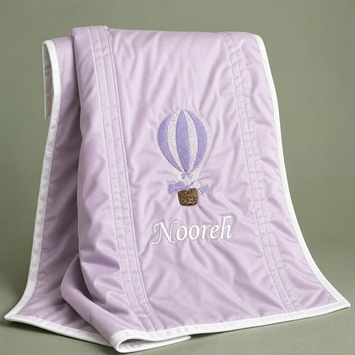 Lilac silk baby wrapping sheet with ivory trim, an embroidered hot air balloon and a name in ivory script