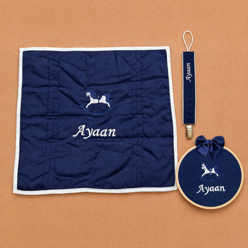 Just the Essentials navy gift bundle laid out flat — personalised silk wrapping sheet, name frame and pacifier holder