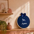 Navy silk name frame in a wooden hoop styled in a nursery setting