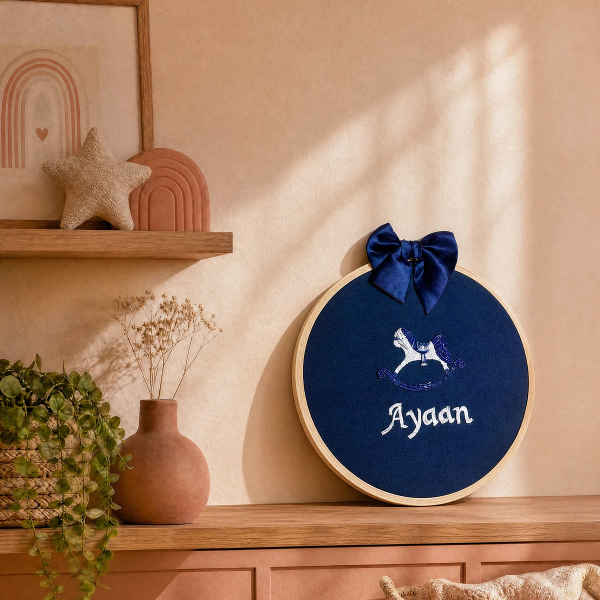 Navy silk name frame in a wooden hoop styled in a nursery setting