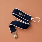 Navy silk pacifier holder styled in a nursery setting