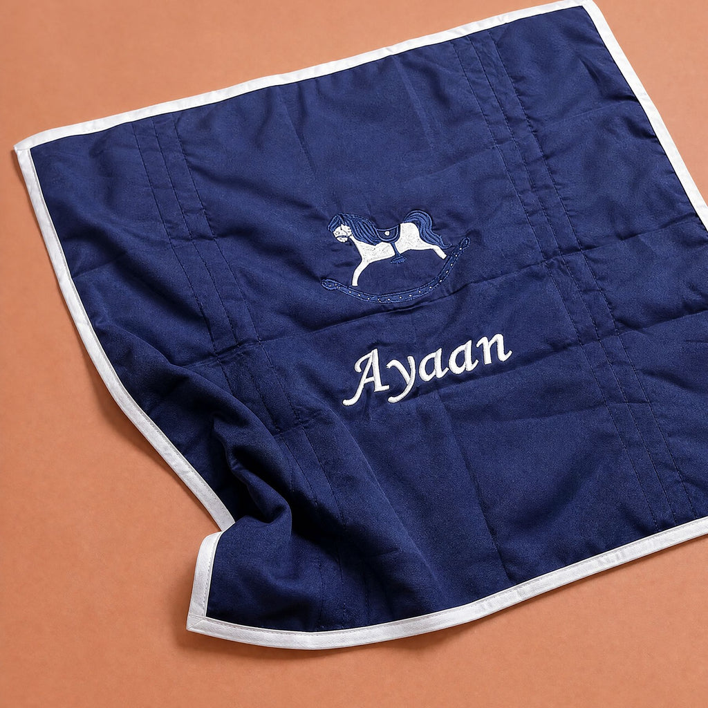 Navy silk baby wrapping sheet with ivory satin binding, an embroidered rocking horse and a name embroidered in ivory script