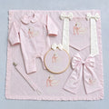 The Grand Arrival pink gift bundle laid out flat — all six personalised pink silk pieces including romper, wrapping sheet, name frame, name flag, announcement bow and pacifier holder