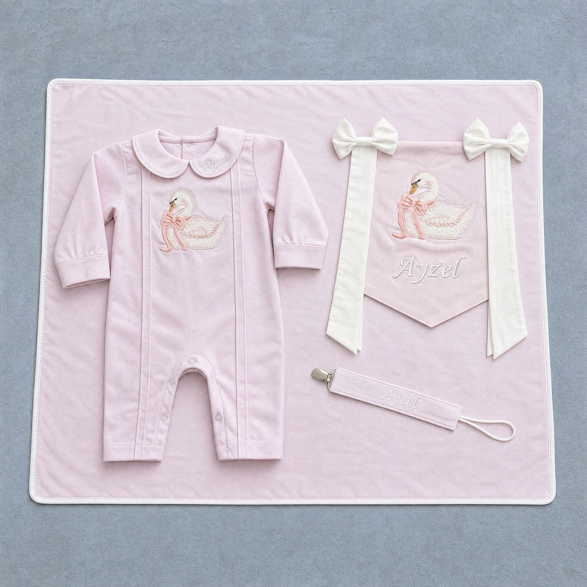 Welcome to the World pink gift bundle laid out flat — personalised pink silk romper, wrapping sheet, name flag and pacifier holder