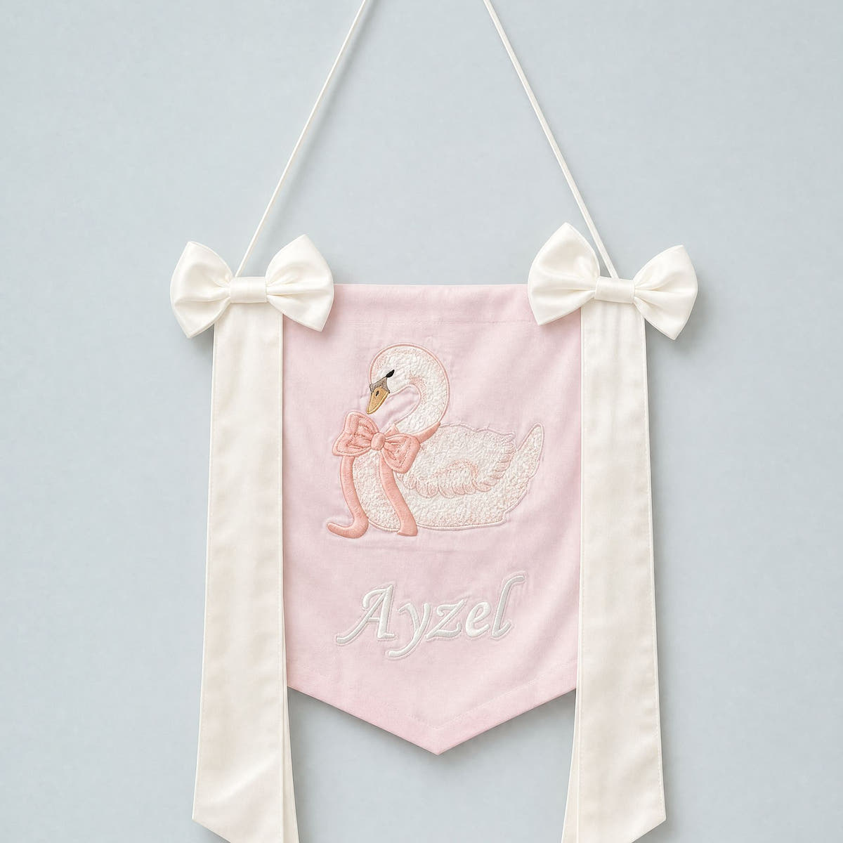 Pink silk name flag with an embroidered swan, ivory silk bows and a baby's name in ivory script
