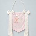Pink silk name flag with an embroidered swan, ivory silk bows and a baby's name in ivory script