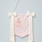 Pink silk name flag with an embroidered swan, ivory silk bows and a baby's name in ivory script