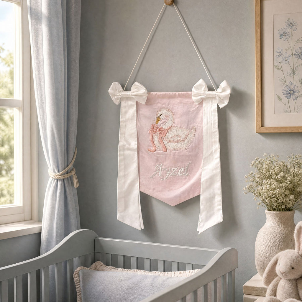 Personalised pink silk name flag hanging on a nursery wall