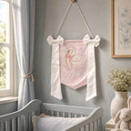 Personalised pink silk name flag hanging on a nursery wall