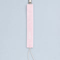 Soft pink silk pacifier holder with white edging, a metal clip, ivory cord loop and a baby's name embroidered in ivory script