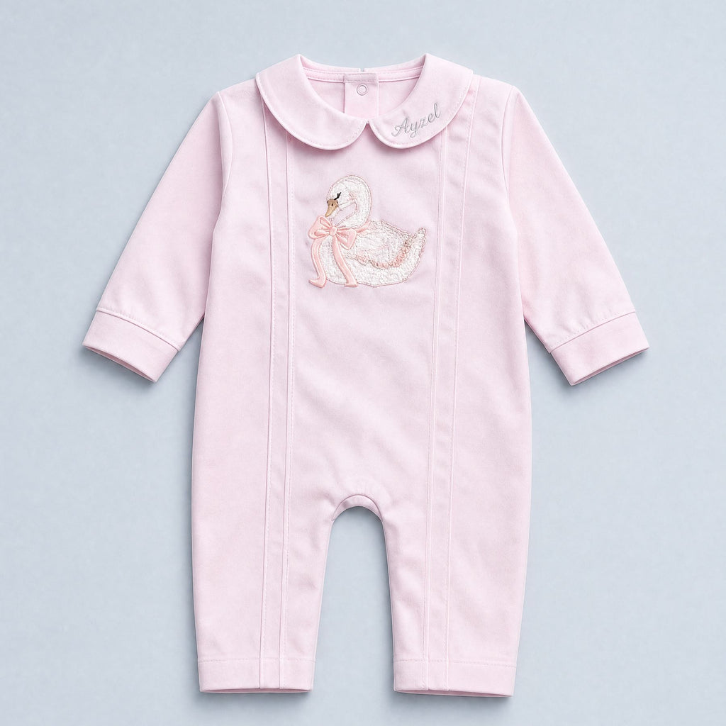 Soft pink silk baby romper with a Peter Pan collar, tonal piping and an embroidered white swan with a pink ribbon bow at the chest