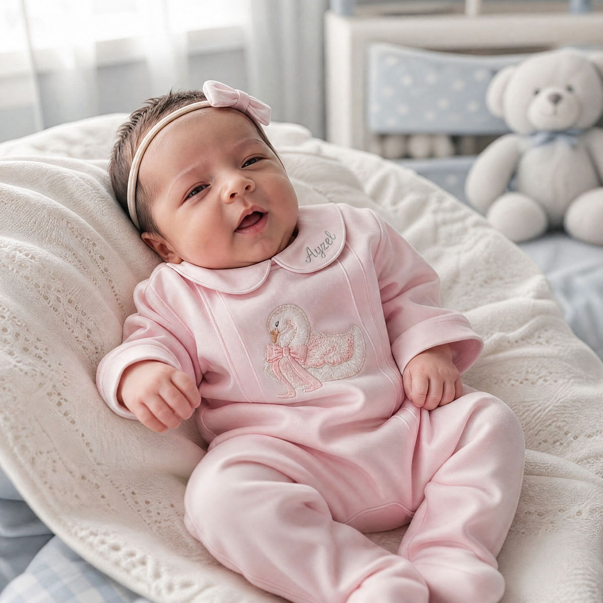 Pink silk Zyra Baby romper with swan embroidery, styled in a nursery setting