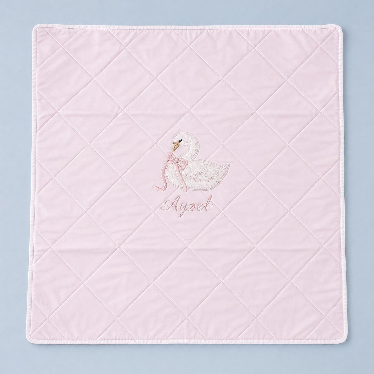 Quilted pink silk baby wrapping sheet with white binding, an embroidered swan and a name in soft pink script