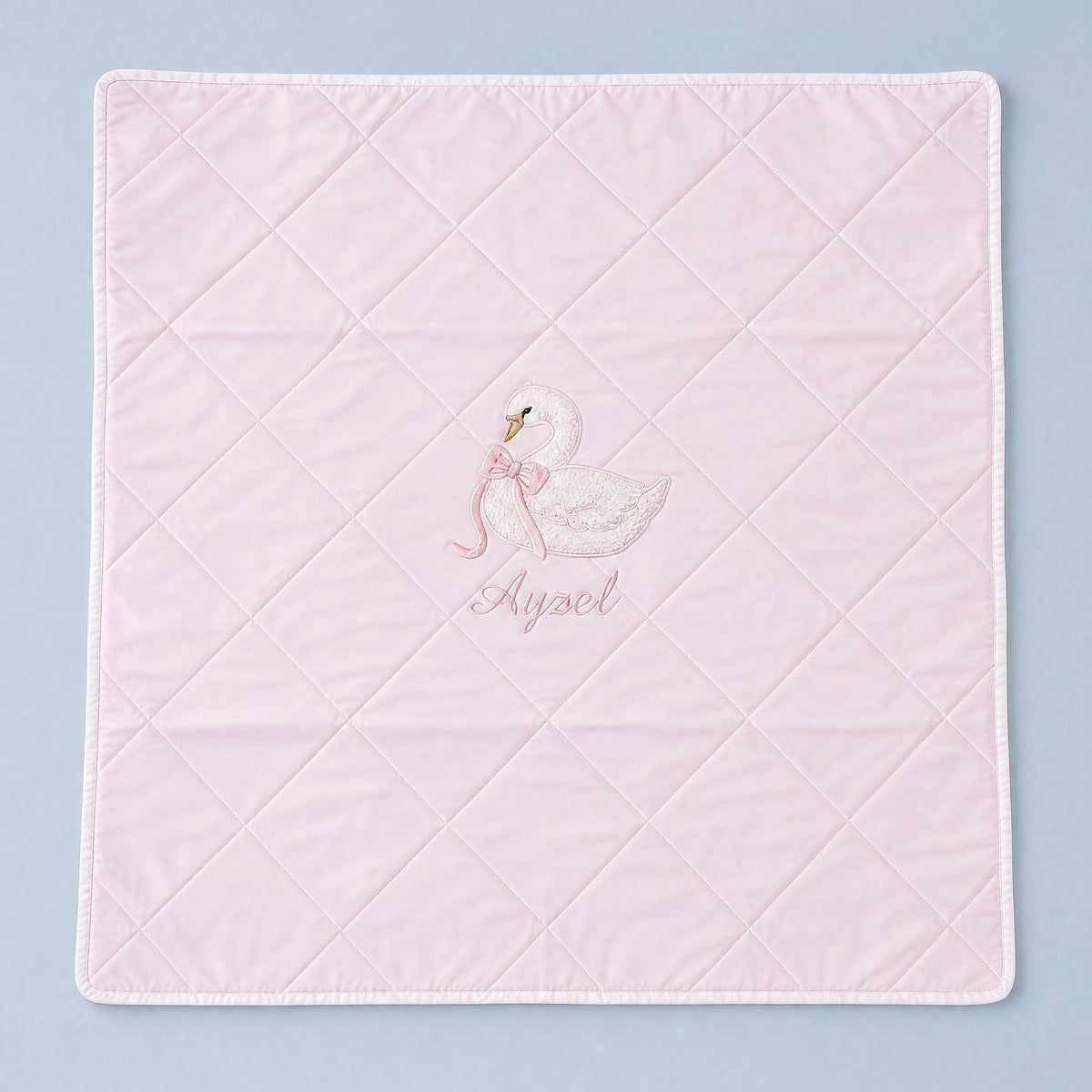 Quilted pink silk baby wrapping sheet with white binding, an embroidered swan and a name in soft pink script