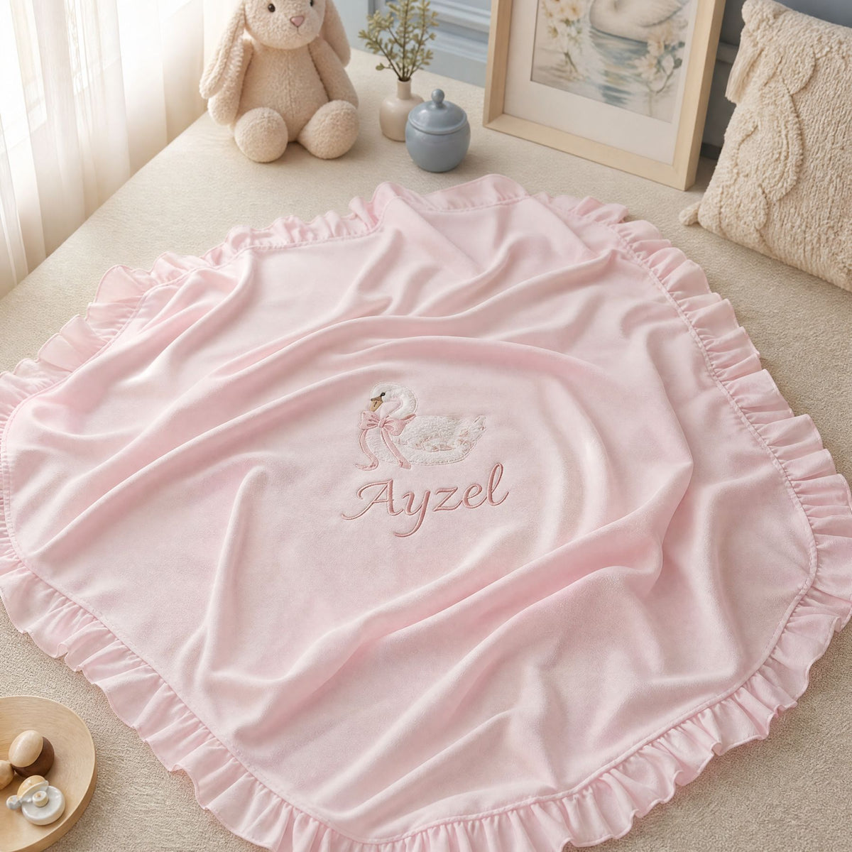 Pink quilted silk wrapping sheet with swan embroidery, styled in a nursery setting