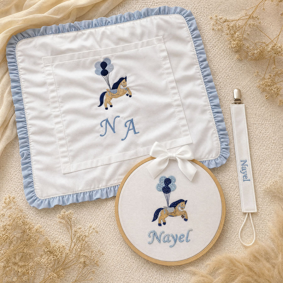 Just the Essentials white and blue gift bundle laid out flat — personalised ivory silk wrapping sheet, name frame and pacifier holder