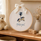 Ivory silk name frame in a wooden hoop, styled in a nursery setting