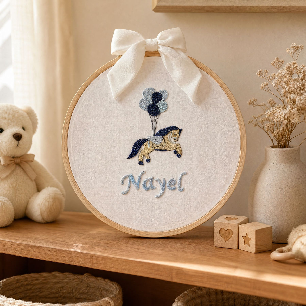 Ivory silk name frame in a wooden hoop, styled in a nursery setting