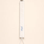 Ivory silk pacifier holder with pale blue detailing and a baby's name embroidered in pale blue script