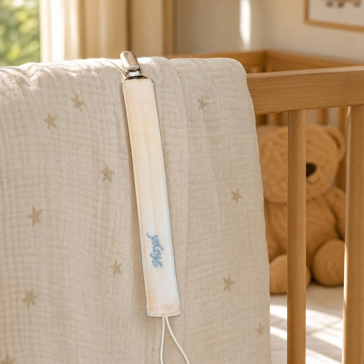 Ivory silk pacifier holder styled in a nursery setting