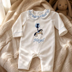 Ivory silk Zyra Baby romper with pale blue detailing, styled in a nursery setting