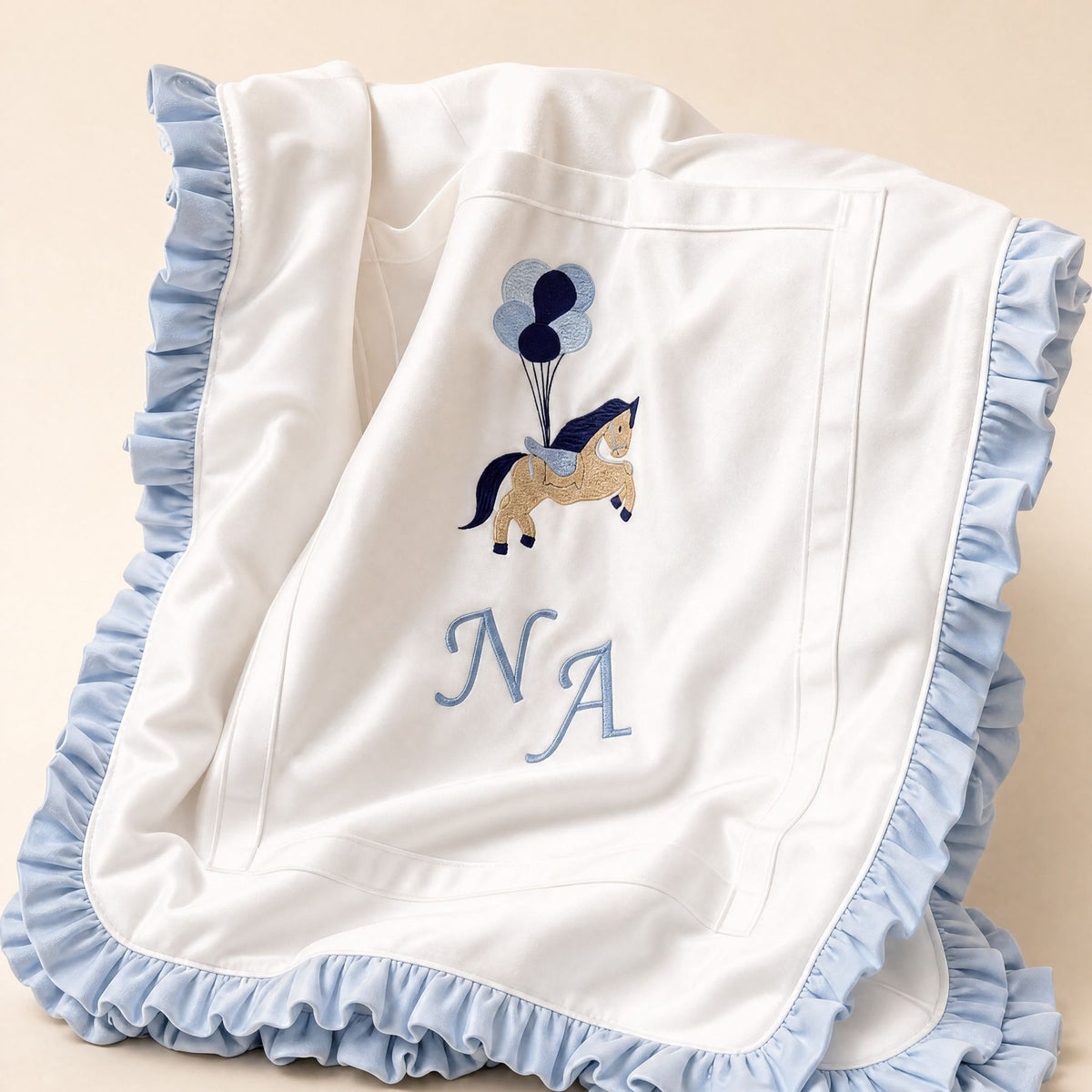 Ivory silk baby wrapping sheet with pale blue trim, an embroidered pony with balloons and a name in pale blue script