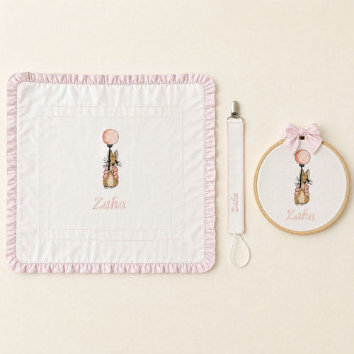 Just the Essentials white and pink gift bundle laid out flat — personalised ivory silk wrapping sheet, name frame and pacifier holder