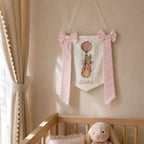 Personalised white and pink silk name flag hanging on a nursery wall