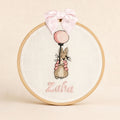 Ivory linen embroidery hoop name frame with a bunny holding a pink balloon, a soft pink silk bow and a baby's name in pink script