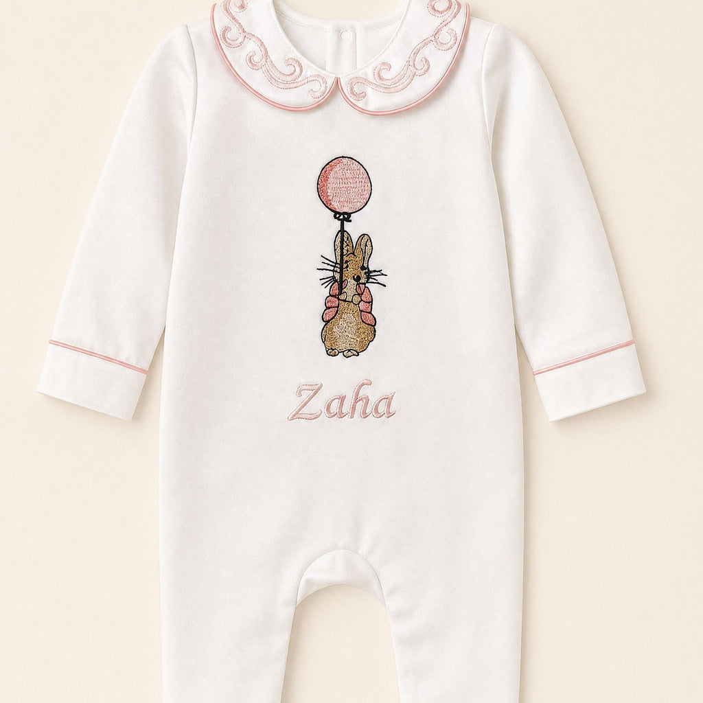 Ivory silk baby romper with pink piping, a scrolled Peter Pan collar and an embroidered bunny holding a pink balloon at the chest