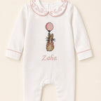 Ivory silk baby romper with pink piping, a scrolled Peter Pan collar and an embroidered bunny holding a pink balloon at the chest